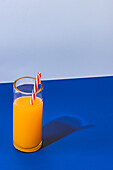 Close up shot of glass of fresh orange juice cocktail on blue background