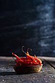 Wooden bowl with dried red hot peppers placed on table against blurred background