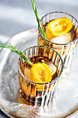 High angle of spicy Margarita cocktails served with ice cubes and sliced of fresh fruits placed on tray against gray background