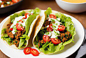 From above of appetizing tacos with lettuce leaves and meat with tomatoes and sour cream served on plate. Generative AI