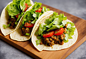 High angle of served appetizing Mexican tacos with spicy chili peppers and cilantro on plate on gray background. Generative AI