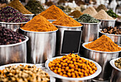 Mehrfarbiger Basar mit gemischten Geschmacksrichtungen von pulverisierten und essbaren Gewürzen, die auf einer Edelstahldose an einem Stand auf einem lokalen Markt platziert sind