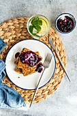 Stack of homemade crepes topped with luscious blueberry jam and a dollop of sour cream, served on a white plate with a fork.