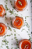 From above jars filled with homemade fruit jam placed on table with green sprigs of thyme