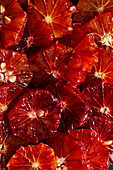 Full frame background of fresh juicy peeled whole ripe bloody oranges served on black surface