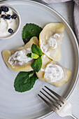 Top view of a tasty traditional Ukrainian dumplings with cherry and sour cream with mint