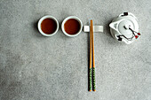 Top view of tea set in Asian style with chopsticks against gray background