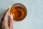 Top view of a hand of an anonymous woman taking a glass of Georgian variety of wine Kisi on white concrete table
