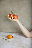 Crop anonymous person holding bunch of fresh ripe red peaches with dripping honey and green leaves placed on table against gray background