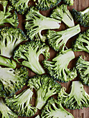 From above green broccoli stems placed on wooden background preparing to cook