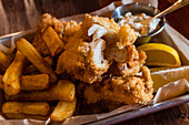 Traditional English dish Fish and chips served with french fries on wooden table