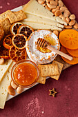 Gourmet cheese platter with honey, dried fruit, and nuts on a rustic table.