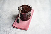 High angle of hot chocolate served in transparent glass with spoon on napkin against blurred background