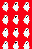 Seamless vector illustration of smiling cartoon ghosts placed in parallel rows against vivid red backdrop