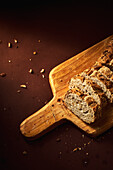 High angle of delicious freshly baked bread with crispy crust sprinkled with mix of seeds and placed on wooden cutting board