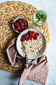 From above healthy breakfast with oatmeal with fresh organic raspberries and homemade lemonade on concrete table