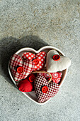 From above heart shaped bowl filled with assorted handmade fabric hearts on a textured concrete background during Valentine's day celebrations