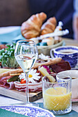 Elegantes Brunch-Set mit einem Glas Weißwein, frischem Croissant und verschiedenen Köstlichkeiten