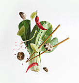 Asiatisches Essenskonzept mit fliegenden Zutaten: Bok choy, Essstäbchen, Limette, Shiitake, Gewürze und Chili auf weißem Hintergrund. Levitation Essen. Frontansicht