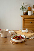Bowl with fresh red strawberries in bowl for cooking on wooden palate over table during jam preparation at home
