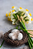 From above easter card concept with nest with eggs and daffodil flowers in bouquet