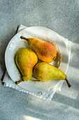 Top view of white marble plate with fresh juicy pears placed on a concrete table