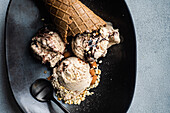 From above focus waffle cones with coffee and chocolate ice cream on the plate on concrete background