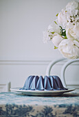 Sweet vegan blue panna cotta dessert on plate placed on table near flowers