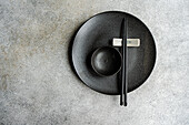 Minimalistischer gedeckter Tisch mit Geschirr und Besteck auf Betonhintergrund