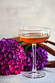 Glas mit frischem Getränk auf dem Tisch in der Nähe von Bouquet von lila Hortensien in braunen Tasche Korb