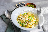 Ein köstlicher Teller Farfalle-Nudeln mit frischer Pesto-Sauce, serviert auf einem sauberen weißen Tischtuch, perfekt für kulinarische Themen