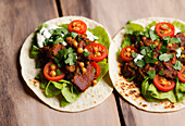 High angle of served appetizing Mexican tacos with spicy chili peppers and cilantro on wood table. Generative AI