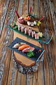 From above of delicious uramaki sushi and nigiri sushi together with sashimi in small bowls on wooden background