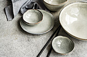 Set of grey ceramic crockery on a concrete background in the same color