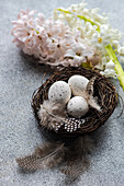 Draufsicht auf ein Nest mit Eiern und Hyazinthenblüten auf einem Betonhintergrund als Konzept für eine Osterkarte
