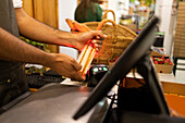 Unrecognizable male seller using scanner to sell bottle of oil for client in modern store at counter during work process