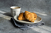 Von oben schwarzer Kaffee und frisch gebackene Croissants auf Betontisch