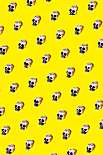 Vector illustration of small human skulls with creepy paint placed in symmetrical rhomb on vibrant yellow background