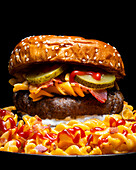 Nahaufnahme eines Hamburgers auf einem Teller mit Makkaroni, Ketchup und Käse vor dunklem Hintergrund