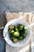 Feijoa fruits are arranged on a ceramic plate, highlighted by sun rays, showcasing a cut-open fruit with spoon.