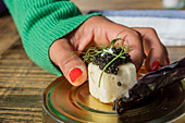 Eine Hand präsentiert ein Gourmet-Fusionsgericht mit Kaviar in einem Michelin-Stern-Restaurant in Zermatt, Schweiz, das lokale und saisonale Zutaten hervorhebt