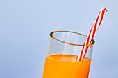 Nahaufnahme eines abgeschnittenen Glases mit frischem Orangensaft-Cocktail auf blauem Hintergrund