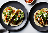 High angle of served appetizing Mexican tacos with spicy chili peppers and cilantro on plate. Generative AI