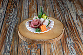 Traditional Japanese sashimi dish with assortment of raw fish served in seashell on wooden background