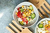 Von oben gesunder Salat mit verschiedenen Gemüsesorten, serviert in einer Schüssel mit Gabel auf einem Tisch mit blauem Hintergrund
