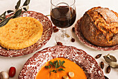 Ein elegantes Abendessen mit spanischem Omelett und Salmorejo mit Croutons, frischem Krustenbrot und einem Glas Rotwein