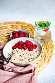 From above healthy breakfast with oatmeal with fresh organic raspberries and homemade lemonade on concrete table