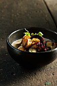 High angle of appetizing traditional Ecuadorian seafood consisting of grilled shrimps and octopus tentacle garnished with herbs and sauce in bowl