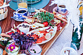 Ein üppig gedeckter Brunch-Tisch mit frischen Blumen, verschiedenen Käsesorten, Räucherlachs, Gebäck und Getränken