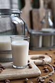 Home made organic horchata drink served in a modern transparent glass near bottle on wooden table in a rustic kitchen